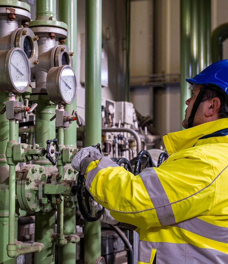 Un tecnico agisce su alcune valvole di pressione di un macchinario per rifiuti