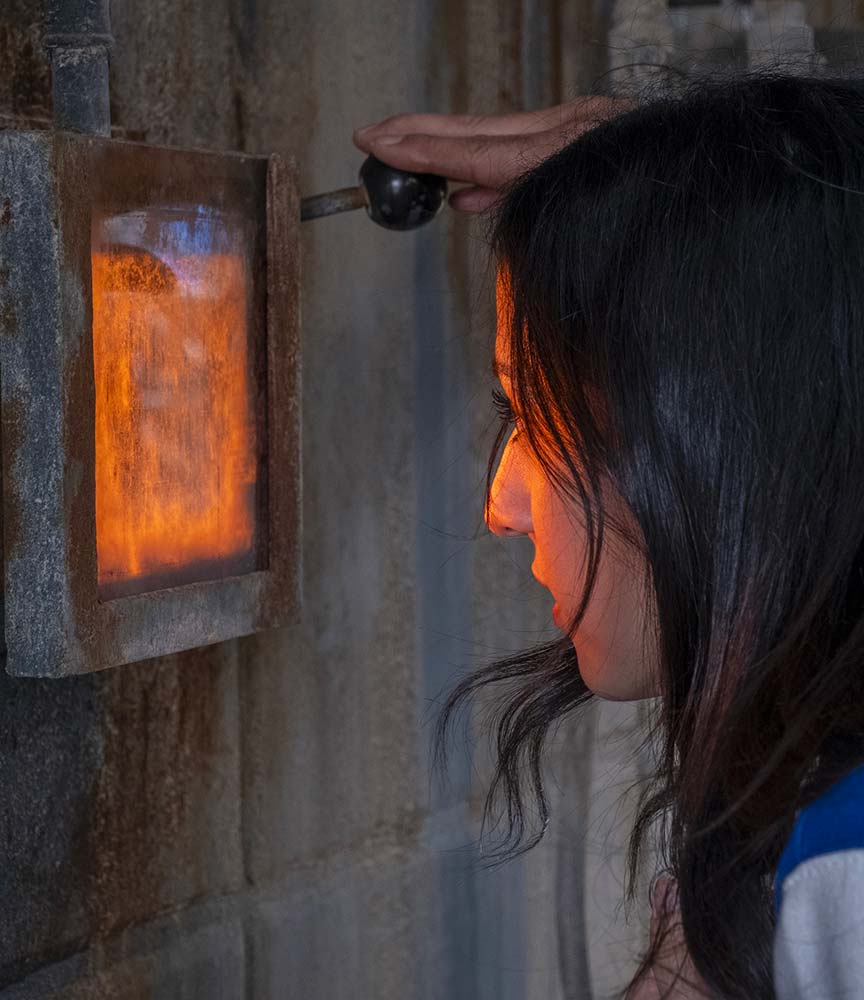 Un tecnico donna guarda, tramite la finestra di sciurezza, l'incenerimento dei rifiuti