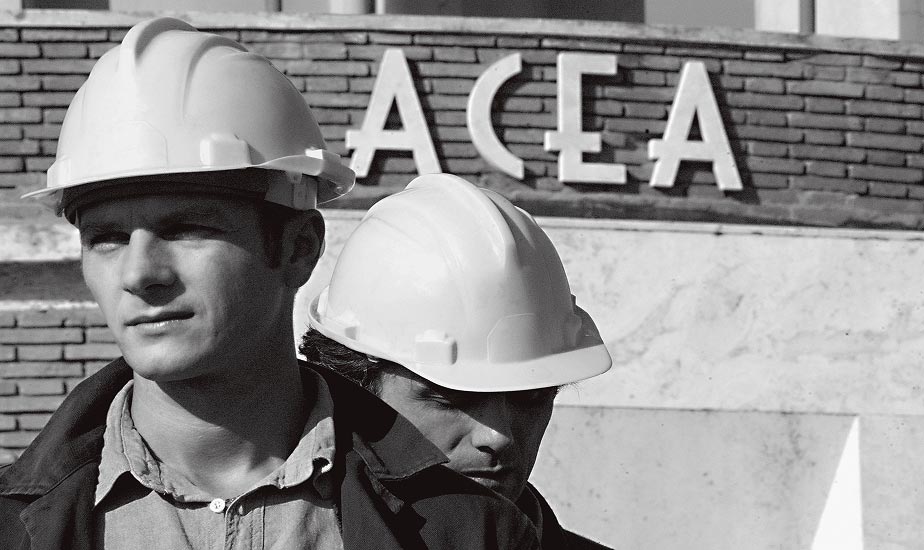 Due operai con caschi protettivi davanti al logo ACEA, simbolo della ripresa post-bellica dell'azienda