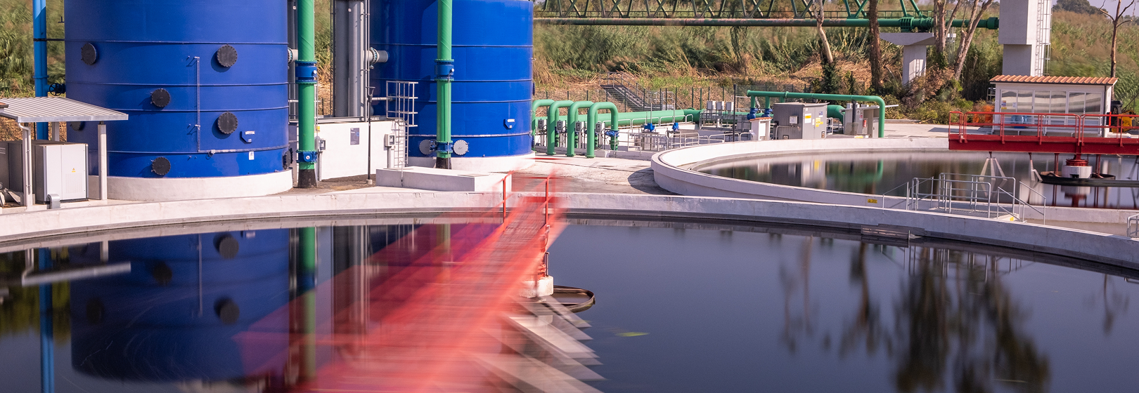 Wastewater treatment plant with circular tanks, green pipes and blue tanks