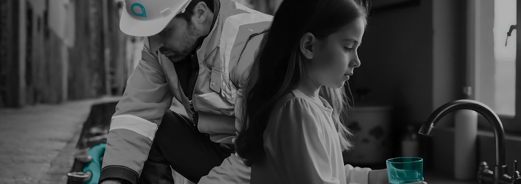 Sulla sinistra un operatore Acea in tuta da lavoro e caschetto bianco con il logo Acea lavora in strada, sulla destra una bambina che riempe un bicchiere d'acqua dal rubinetto
