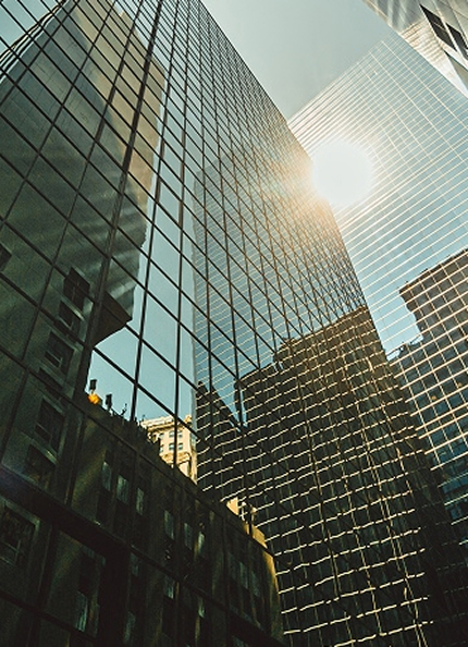 Vista dal basso di grattacieli moderni con finestre e il sole che splende nel cielo