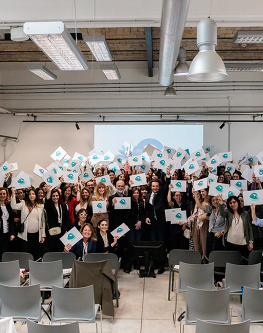 Gruppo di dipendenti Acea posano per la fotocamera mentre reggono un foglio bianco con sopra disegnato un pesce verde illustrato, protagonista del libro per bambini "Un fiume di emozioni"