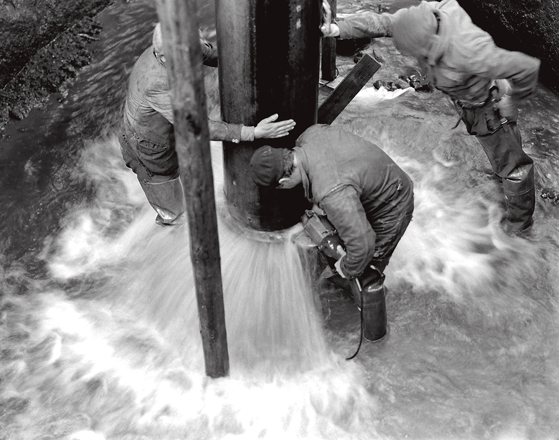 foto in bianco e nero di operai che lavorano nell'acquedotto pieno di acqua