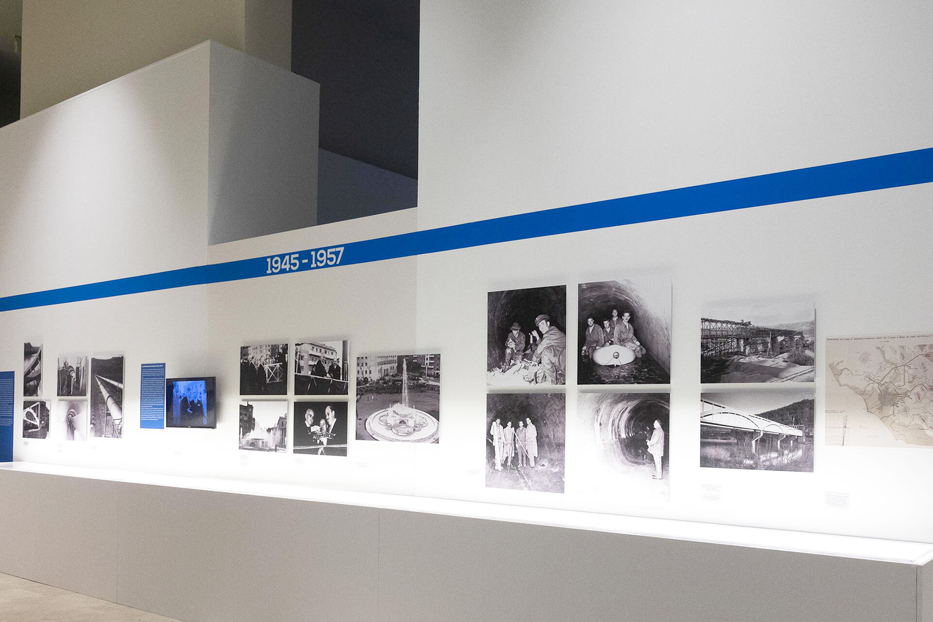 Foto di una parete in cui sono appese tutte le foto del periodo 1945-1957 riguardanti l'acquedotto del Peschiera