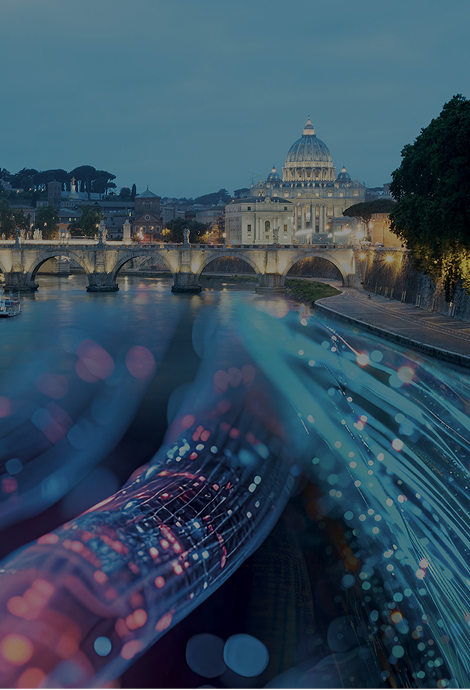 Sullo sfondo c'è il Vaticano e davanti un ponte, entrambi illuminati. Sovrapposto sul Tevere passano dei cavi elettrici colorati