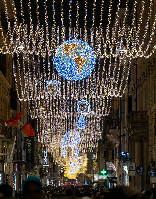 Vista in prospettiva delle luminarie di via del corso con in primo piano la luminaria del mappamondo