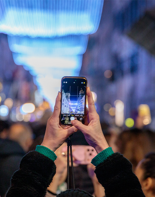 Persona che scatta una foto alle luminarie di Natale 2025 di Acea