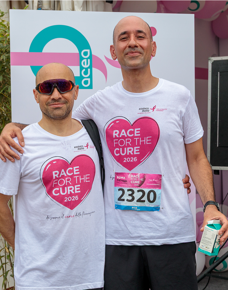 Two participants in the Race for the Cure event on May 10 pose with smiles on their faces, both wearing T-shirts with the event logo