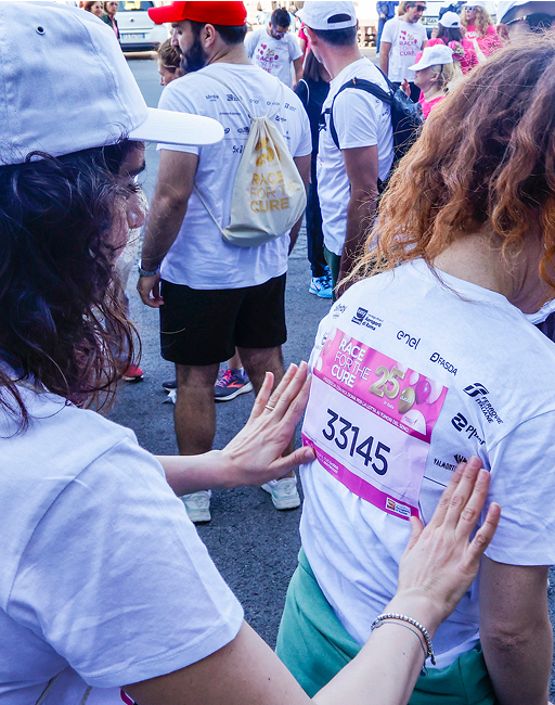 Donan applica l'adesivo con il numero concorrente ad un'altra donna durante la maratona di Run for the Cure