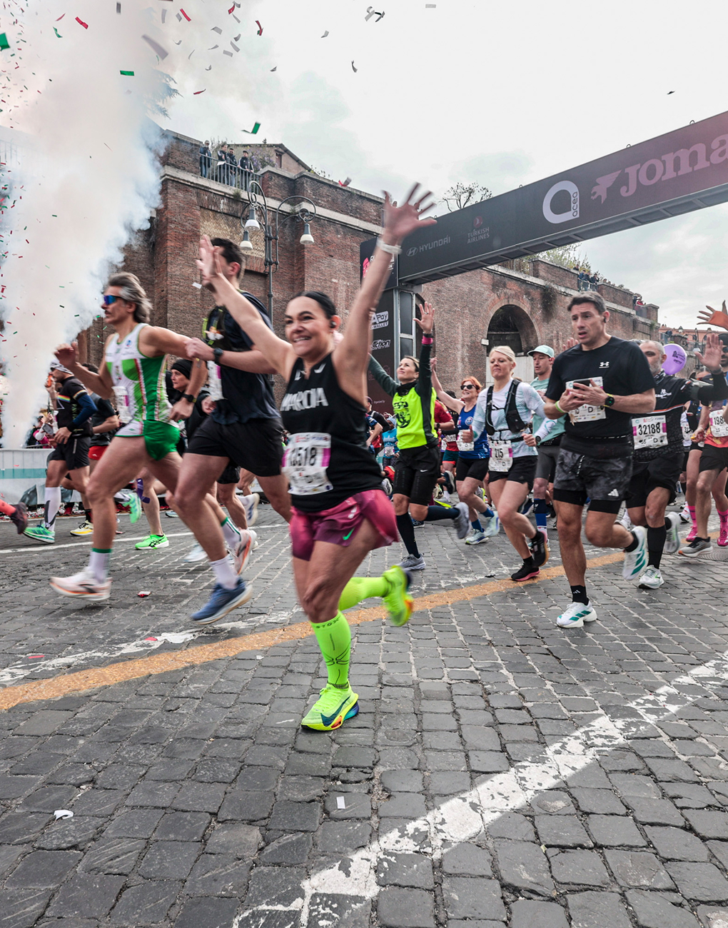 An athlete celebrates at the start of the Acea Run Rome The Marathon 2026, with the starting sign bearing the Acea logo in the background