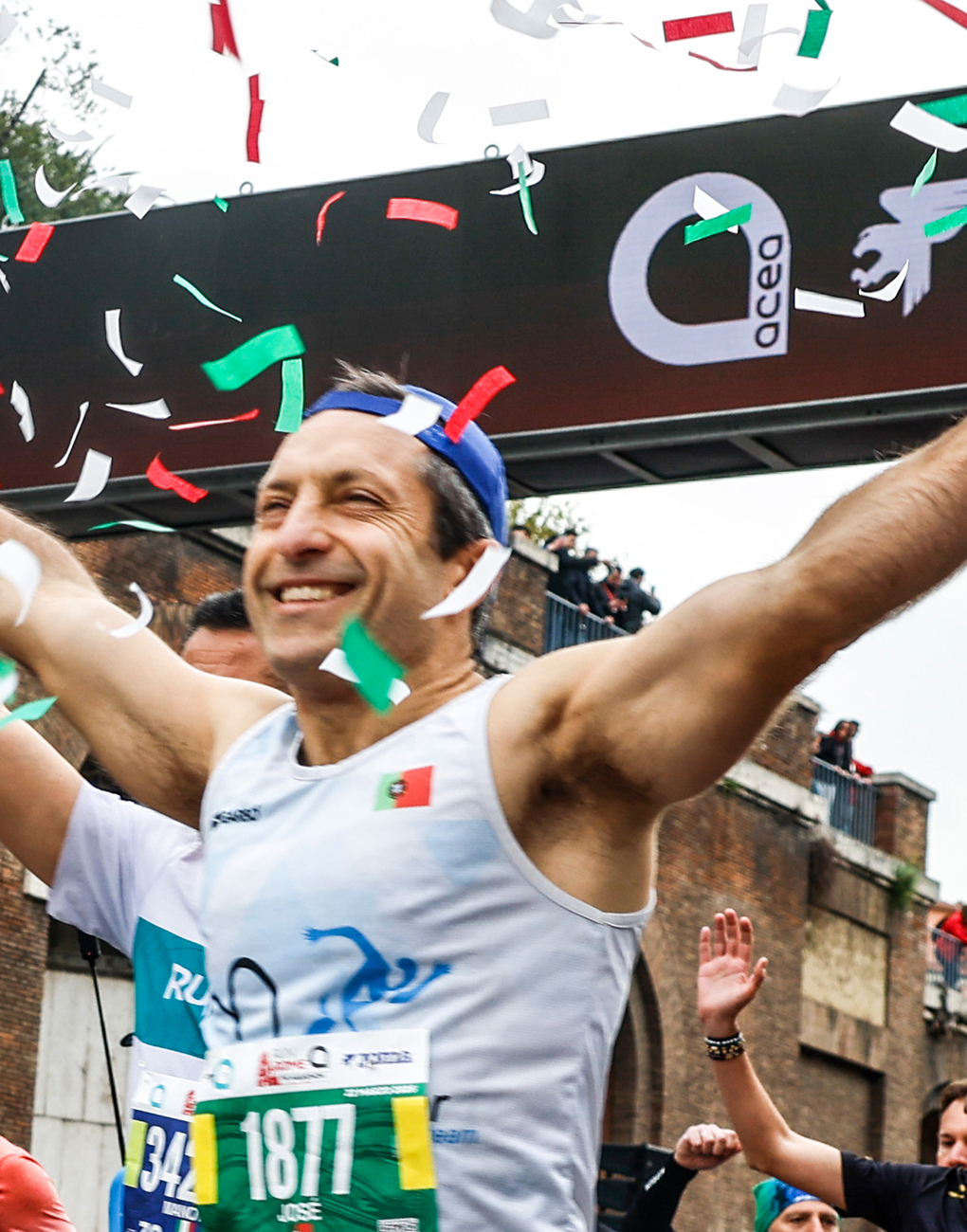 Close-up of a smiling runner at the start of the Acea Run Rome The Marathon 2026, with the Acea logo in the background