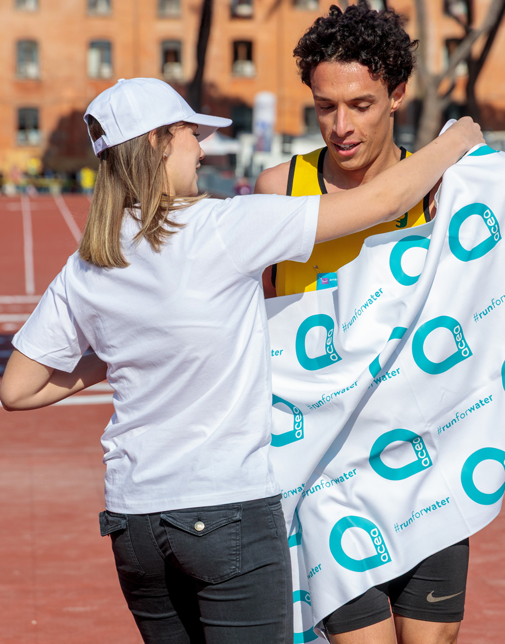 A runner is wrapped in a towel bearing the acea logo