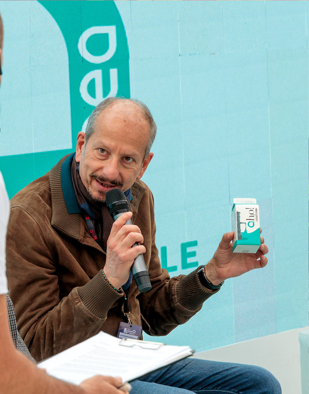 Virman Cusenza, Chief Communications Officer at Acea, speaks with the interviewer while holding a carton of ah2o! water.