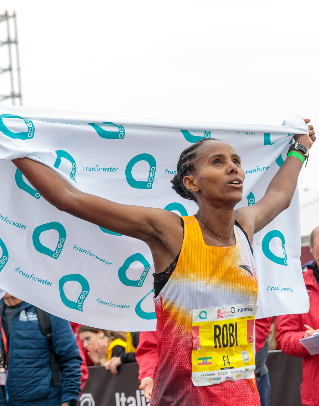 Tadesse Robi crosses the finish line at the 2026 Acea Run Rome Marathon carrying the Acea flag