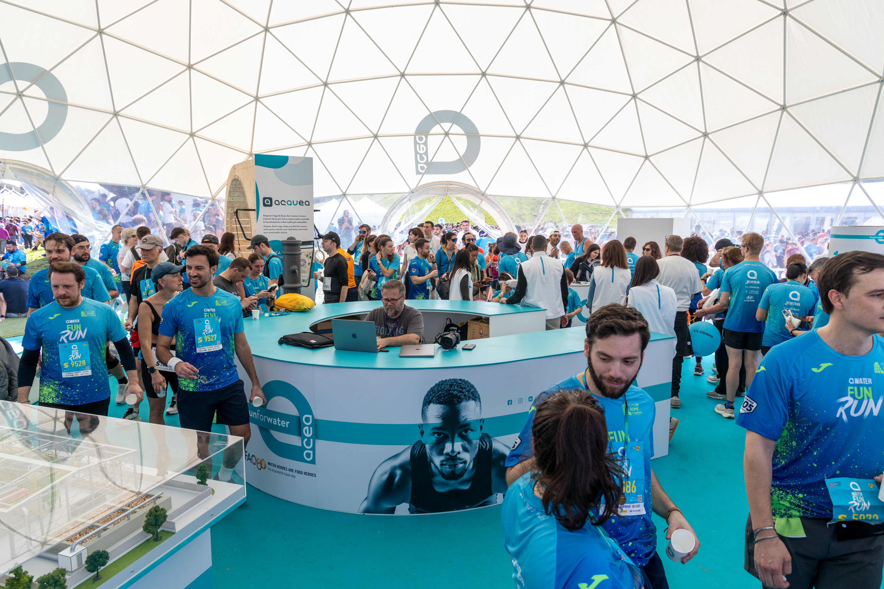 Partecipanti alla maratona riuniti sotto un tendone prima dell'inizio dell'evento