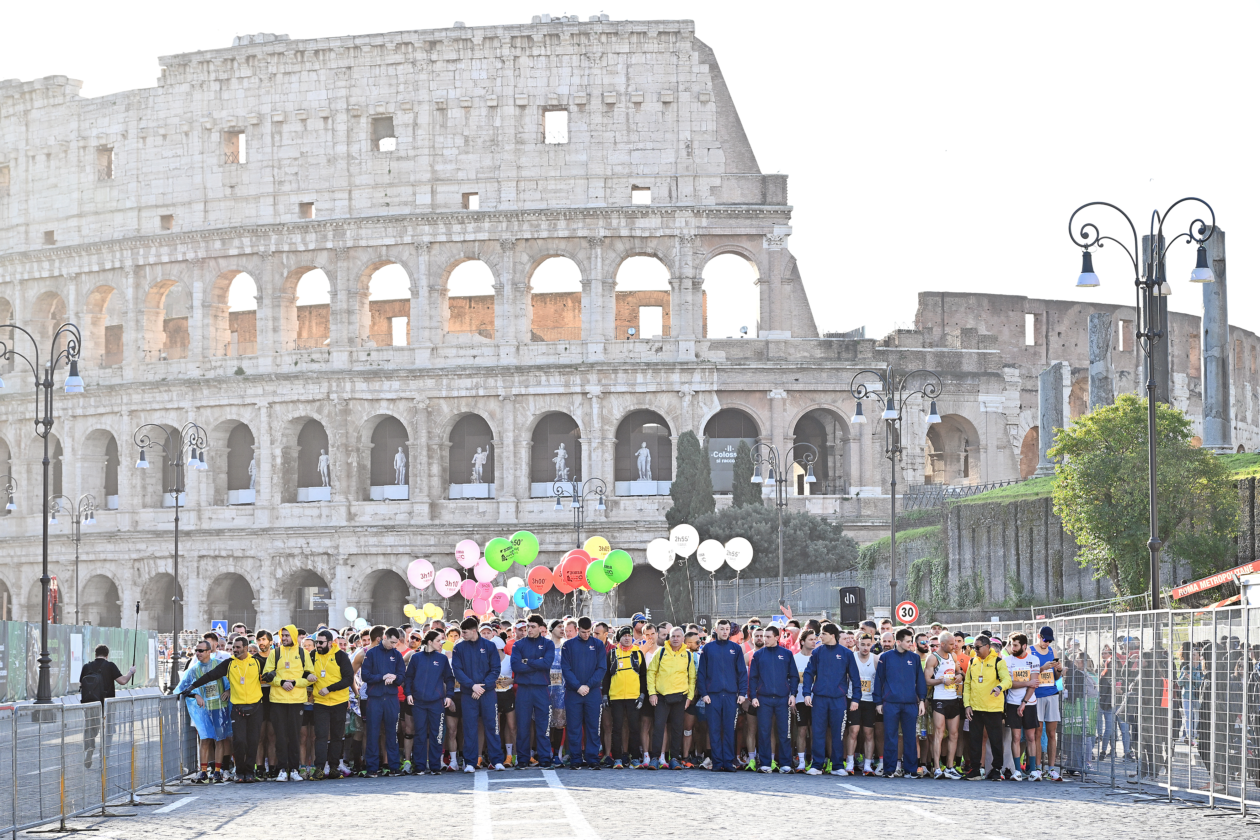 Alcuni dei partecipanti alla matatona riuniti per una foto con alle spalle il colosseo. Alcuni di loro tengono dei palloncini colorati