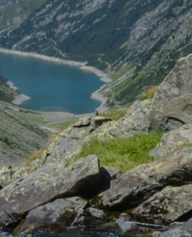 Paesaggio montano con un lago al centro, circondato da pendii rocciosi e vegetazione