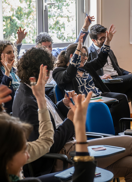 Un gruppo diversificato di professionisti partecipa attivamente a una sessione collaborativa, alzando le mani in segno di partecipazione. L'ambiente luminoso e l'entusiasmo dei partecipanti riflettono i valori di inclusione, diversità e collaborazione promossi da Acea.