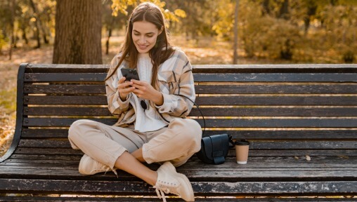 Ragazza che usa lo smartphone su una panchina