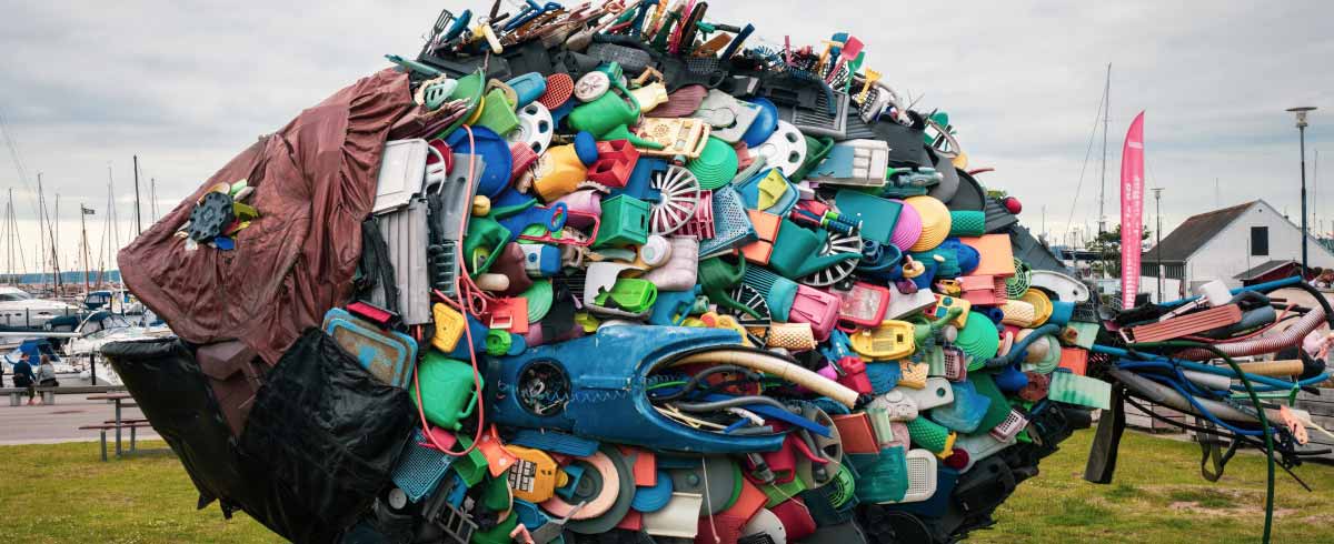 Installazione artistica di un pesce composto di rifiuti in plastica localizzata in una zona portuale