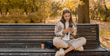 Ragazza che usa lo smartphone su una panchina