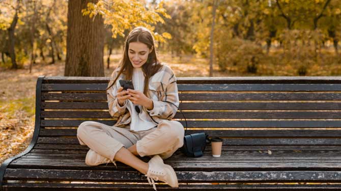 Ragazza che usa lo smartphone seduta sulla panchina