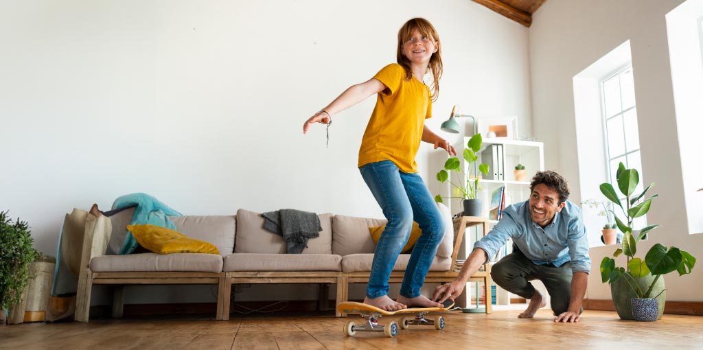 Padre e figlia che giocano con lo skateboard in casa