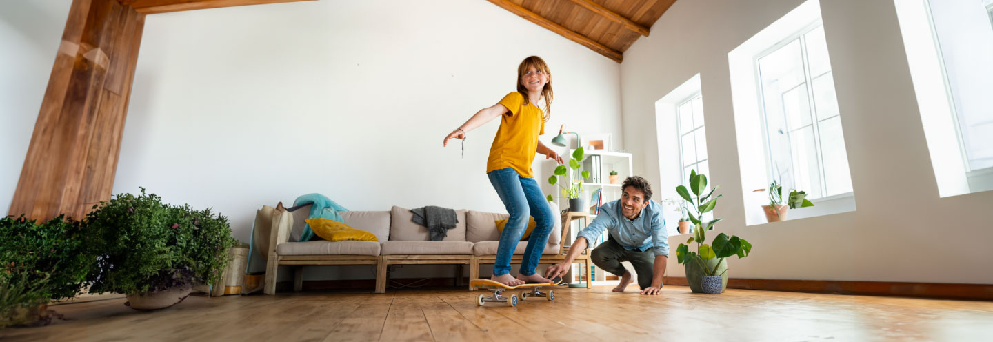 Padre e figlia che giocano con lo skateboard in casa