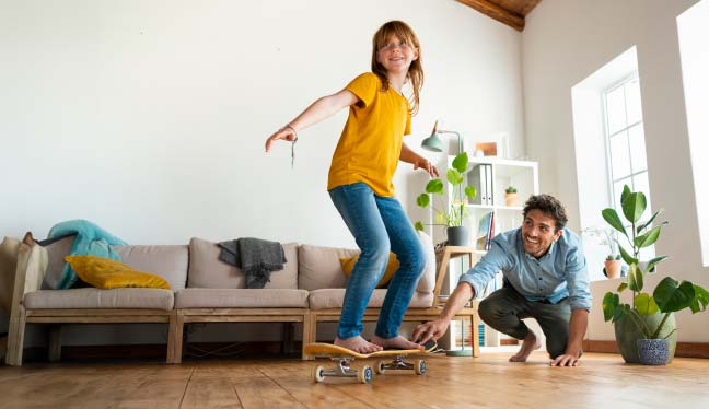 Padre e figlia che giocano con lo skateboard in casa
