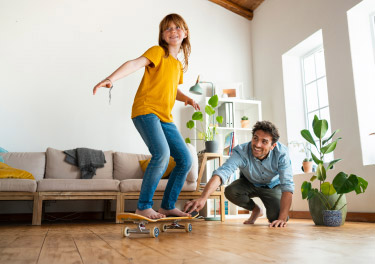 Padre e figlia che giocano con lo skateboard in casa