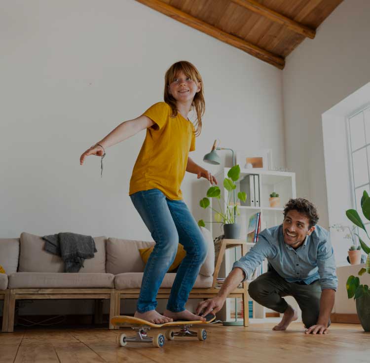 Padre e figlia che giocano con lo skateboard in casa