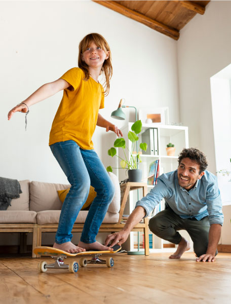 Padre e figlia che giocano con lo skateboard in casa