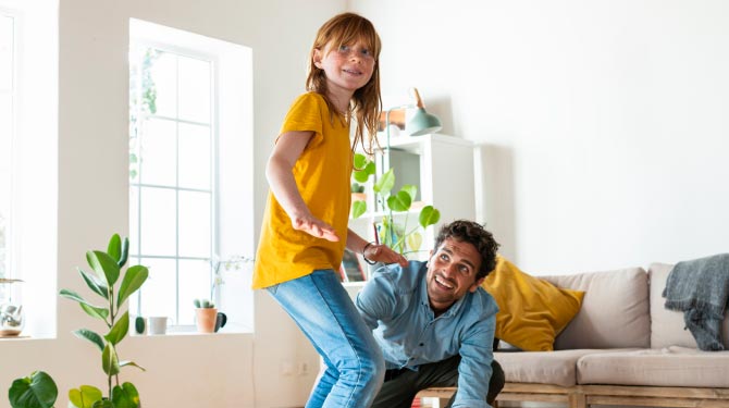 Padre e figlia che giocano con lo skateboard in casa