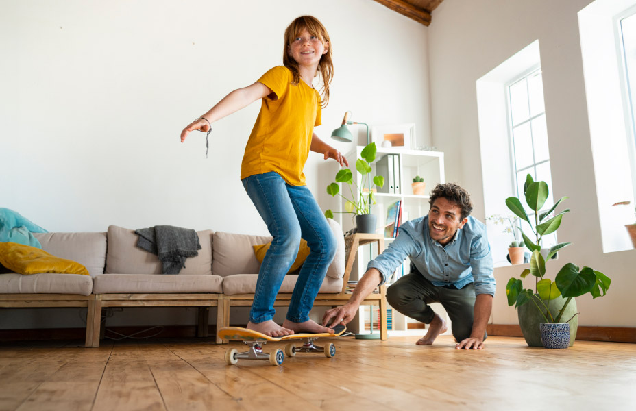 Padre e figlia che giocano con lo skateboard in casa