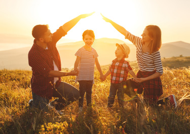 Famiglia che gioca in un prato al tramonto